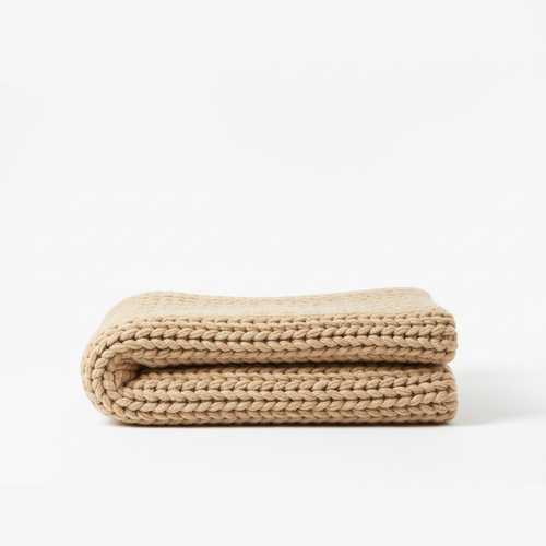 Cozy chunky knitted throw blanket in warm beige on white background